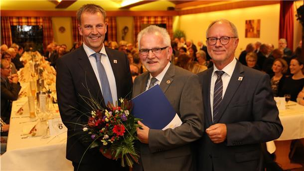 Drei Männer in einem Saal schütteln sich die Hände.