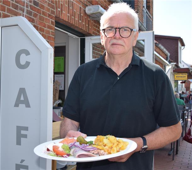 Ein älterer Herr steht neben dem Restaurant "Dat Havenhuus" in Fedderwardersiel. 