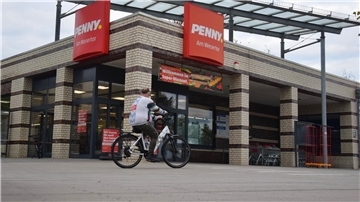 Ein Radfahrer fährt an einem Supermarkt vorbei