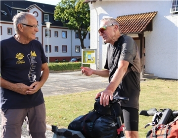 Zwei Männer und ein Fahrrad vor Kirche
