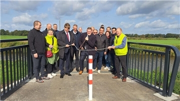 Der Radweg ist eröffnet: Der Schiffdorfer Bürgermeister Henrik Wärner (CDU) durchtrennt symbolisch eine Kette auf der neuen Brücke über die Alte Geeste.