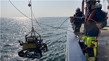 Ein Forschungsteam mit einem Roboter auf hoher See.