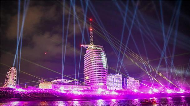 Der Deich in Bremerhaven ist während der Sail 2025 in pinkes Licht gehüllt.