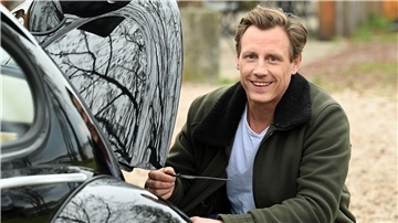 Der Schauspieler Patrick Kalupa mit seinem Oldtimer VW Käfer.