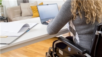 Frau, die im Rollstuhl sitzt, arbeitet am Laptop