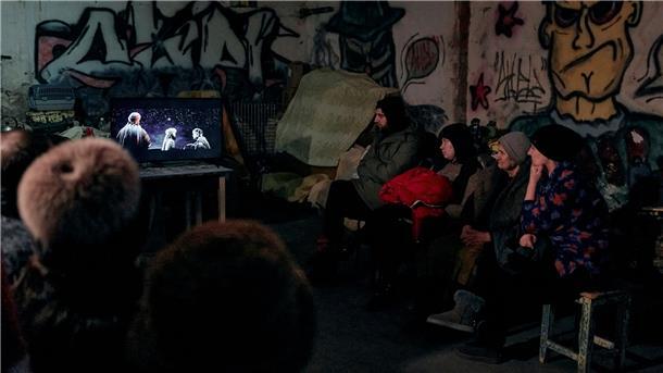 Krieg gegen die Ukraine: So ist die Lage Der Strom kommt von einem Generator: In einem Keller eines Wohnhauses, der als Bunker genutzt wird, schauen sich Menschen einen religiösen Weihnachtsfilm an.