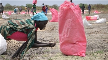 Der tägliche Kampf gegen den Hunger: Eine Frau im Südsüdan sammelt Hirse vom Boden auf, die in Säcken über der Stadt abgeworfen wurden.