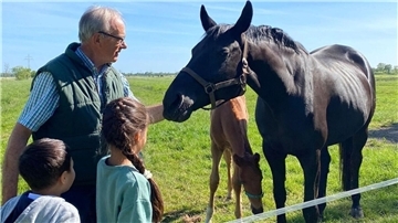 Der Tierhalter Gerhard von Holten - hier mit zwei interessierten Kindern aus der Ukraine auf der Pferdeweide - möchte seine Weidetiere besser vor dem Wolf schützen.
