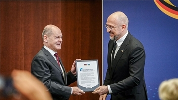 Der ukrainische Premierminister Denys Schmyhal überreicht Bundeskanzler Olaf Scholz beim 6. Deutsch-Ukrainischen Businessforum der DIHK ein Zertifikat für die Rheinmetall Joint-Venture Registrierung für die Ukraine.