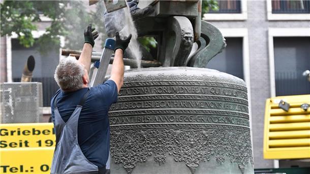 Den tiefen Klang zurückbringen Der Vergleich zu diesen Männern zeigt, wie groß die Gloria-Glocke ist.