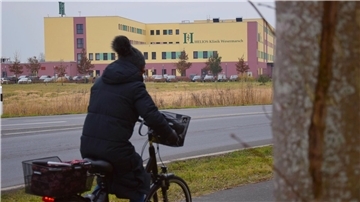 Eine Frau fährt mit dem Fahrrad an der Helios-Klinik Wesermarsch vorbei. 