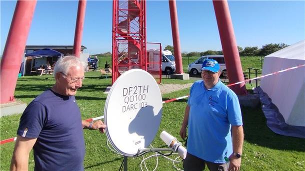 Zwei Männer mit einer Satellitenschüssel.