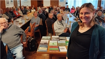 Eine Frau steht vor einer großen Gruppe von Menschen.