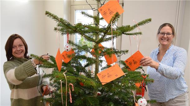 Zwei Frauen schmücken einen Weihnachtsbaum.