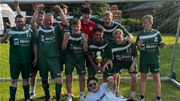 Ein Fußballteam steht im Fußballtor und jubelt.