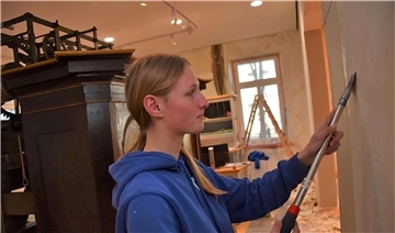 Derzeit laufen die Malerarbeiten im Erdgeschoss des Museums. Das Foto zeigt Luise Pieper, Auszubildende bei der Firma Marcel Koopmann, die gerade dabei ist, die alte Tapete von den Wänden zu kratzen.