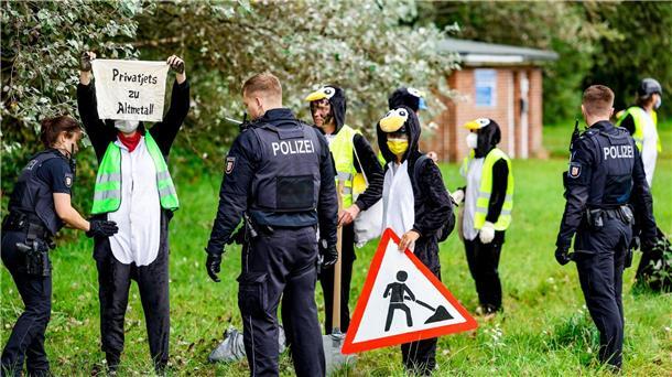 Klima-Protest in Pinguinkostümen am Sylter Flughafen Die Aktivistin werden von Polizisten überprüft.