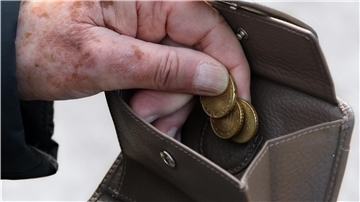Senior greift im Portemonnaie nach Münzen. 