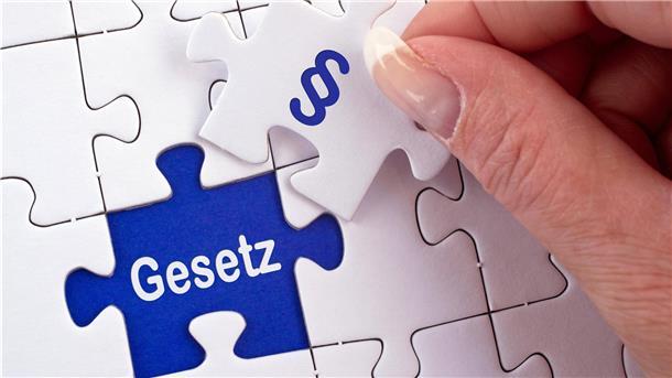 Eine Hand hält ein Puzzleteil mit der Aufschrift "Gesetz".