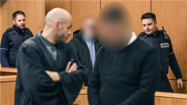 Explosion im Modegeschäft - Vater und Sohn vor Gericht Die Angeklagten werden von Justizbeamten in den Gerichtssaal geführt.