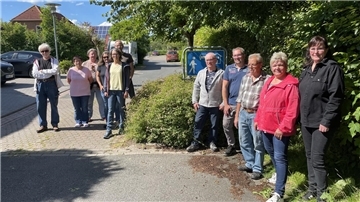 Gruppe von Menschen vor einem Straßenschild.