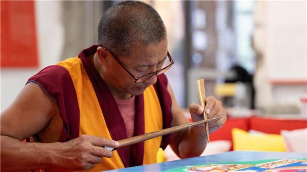 Bild aus buntem Sand Die Arbeit am Sandmandala erfordert Ruhe und Geduld.
