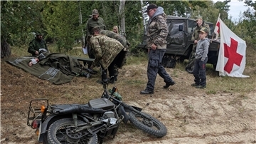 Mehrere Männer, ein liegendes Motorrad und ein Jeep