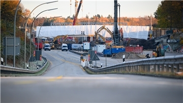 Bagger, Kräne und weitere Baufahrzeuge arbeiten an Brücken über die A7.