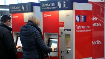 Eine Frau zieht an einem Automaten ein Ticket für die Bahn.
