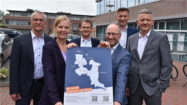 Fünf Männer und eine Frau mit einem Plakat. Es handelt sich um die Vorstände der  Raiffeisenbank Butjadingen-Abbehausen, der Raiffeisen-Volksbank Varel-Nordenham und der Volksbank Jever. 