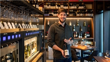 Selbst gezapft, perfekt genossen: Das ist die Bar Rique in Bremen Ein Mann hält eine Weinflasche in der Hand.