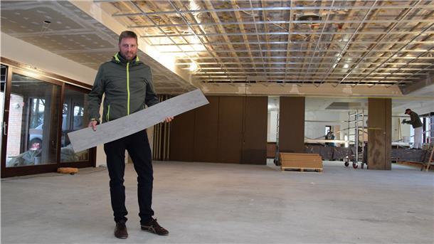 Die Bauarbeiten im Rockstedter „Haus im Löh“ schreiten voran. Der stellvertretende Gemeindebürgermeister Volker Borchers zeigt den Belag, der den Fußboden zieren soll.