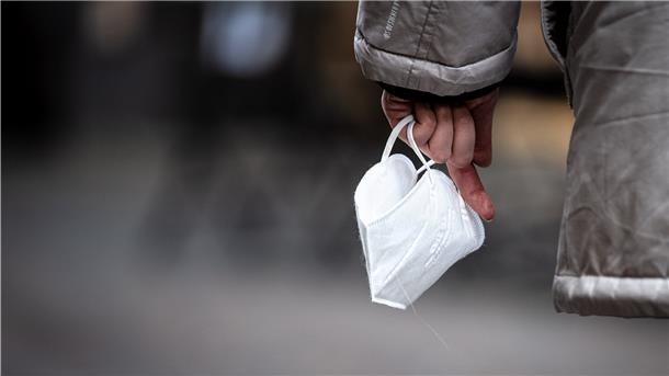 Eine Passantin hält eine FFP-2 Maske in der Hand.