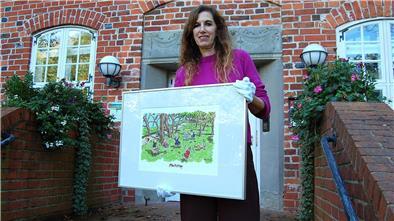 Unbehagen im Bremischen: Ausstellung mit Cartoons von Bettina Bexte Eine Frau hält einen Cartoon in einem Bilderrahmen hoch.