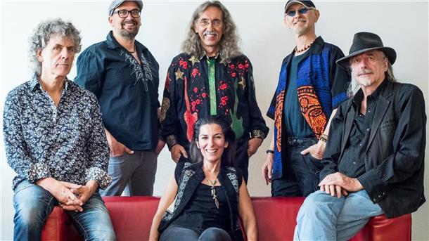 Die Mitglieder der Kultband Bröselmaschine auf und hinter einem roten Sofa. 