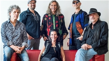 Die Mitglieder der Kultband Bröselmaschine auf und hinter einem roten Sofa. 