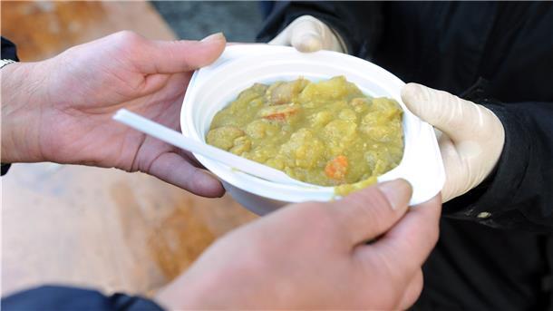 Ein mittelloser Mann erhält einen Teller Erbsensuppe. 
