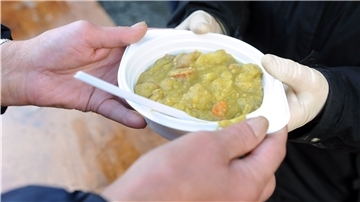 Ein mittelloser Mann erhält einen Teller Erbsensuppe. 