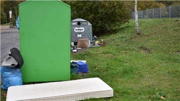 Müll liegt neben einem großen grünen Kasten.