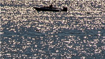 Ein kleines Boot ist im Seekanal in Warnemünde unterwegs. Bei sommerlichen Temperaturen und Sonnenschein zieht es Urlauber und Einwohner an die Strände entlang der Ostsee.