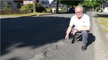 Ein Mann zeigt auf Schlaglöcher