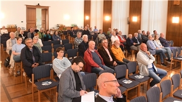 Menschen sitzen in einem Raum und hören zu.