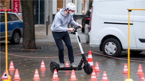 Ein Junge fährt mit dem E-Scooter. 
