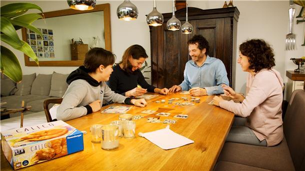 Die Familie gemeinsam am Tisch mit Spielen beschäftigt - genau richtig an trüben Herbsttagen.