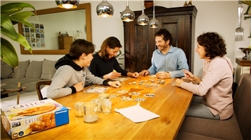 Die Familie gemeinsam am Tisch mit Spielen beschäftigt - genau richtig an trüben Herbsttagen.