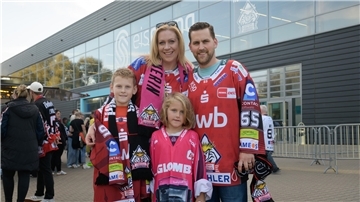 Eine Familie posiert vor der Eisarena Bremerhaven in Trikots der Fischtown Pinguins