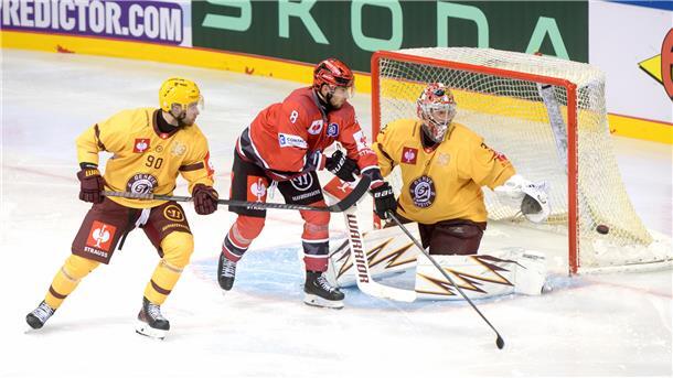 Ein Eishockey-Spieler fährt vor dem Tor des Gegners und versucht den Puck ins Tor zu bekommen. 