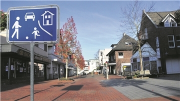 Die Fotomontage zeigt ein Spielstraßenschild in der Fußgängerzone.