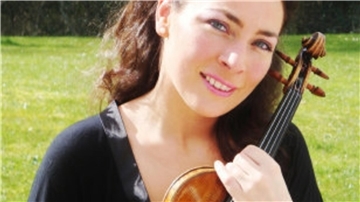 Eine lächelnde Frau hält eine Geige in der Hand. 