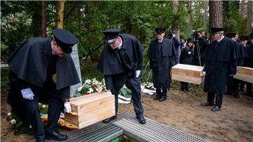 Die Gebeinekisten mit menschlichen Knochen werden nach der Trauerfeier in ein Grab auf dem Waldfriedhof Berlin-Dahlem hinabgelassen.